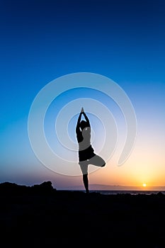 Woman doing yoga sunset silhouette