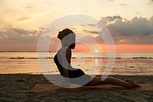 woman doing yoga upward facing dog pose on beach