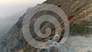 Woman doing yoga Urdva Mukha Svanasana Pose on the top of mountain at sunset. Aerial beautiful footage view on the
