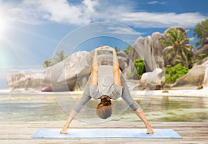 Woman doing yoga wide-legged forward bend on beach