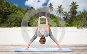 Woman doing yoga wide-legged forward bend on beach