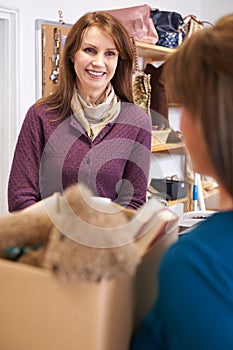 Woman Donating Unwanted Items To Charity Shop