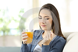 Woman doubting between vitamin pill or orange juice photo