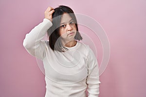 Woman with down syndrome standing over pink background confuse and wondering about question