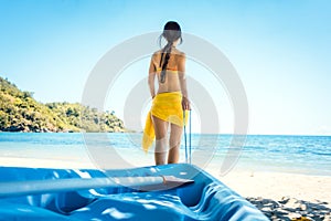 Woman dragging her boat to the water on the beach