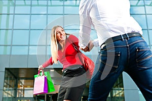 Woman dragging man into shopping mall