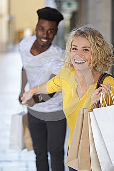 Woman dragging reluctant boyfriend shopping
