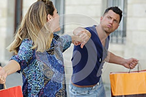 Woman dragging reluctant man back into shops