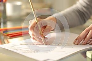 Woman drawing line with pencil and ruler on a desk at home