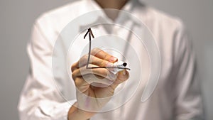 Woman drawing Raise Revenue diagram with red up arrow on transparent screen.