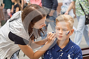 Woman drawing russian flag on the cheek of the young boy sport fan