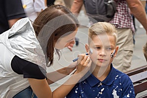 Woman drawing russian flag on the cheek of the young boy sport fan