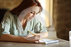 Woman drawing or taking notes on notebook at home