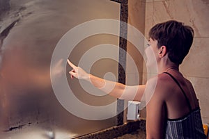 A woman draws a heart in the mirror.The heart is fingerprinted on the glass in bathroom. People concept