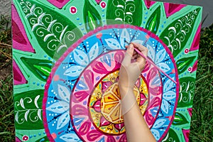 Woman draws a mandala, hand with a brush close-up