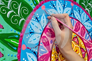 Woman draws a mandala, hand with a brush close-up