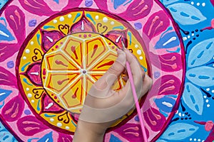 Woman draws a mandala, hand with a brush close-up