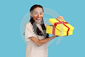 Woman with dreadlocks looking into gift box, opening present and looking at camera with happiness.