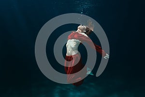 Woman in dress on the bottom underwater.