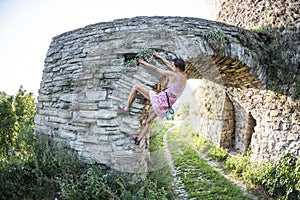 A woman in a dress is climbing a brick wall