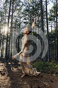 A woman in a dress is dancing in the woods in nature barefoot