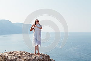 Woman in dress looks at the ocean view from the cliff