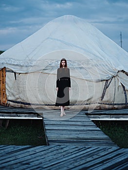 A woman in a dress near the traditional Mongolian dwelling yurt