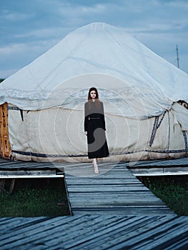 A woman in a dress near the traditional Mongolian dwelling yurt