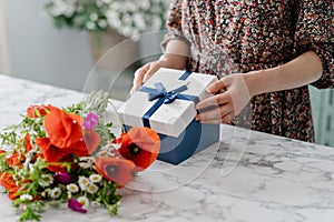 Woman in dress opening gift box indoors