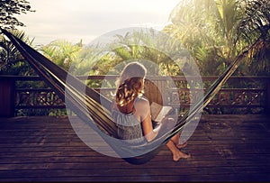 Woman in a dress reading book in a hammock in the jungle at suns