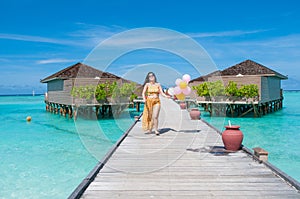 Woman in dress running on tropical beach. Summer vacation at Maldives