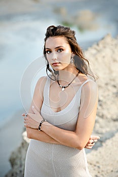 Woman in dress standing separately on an empty sandy beach near the sea