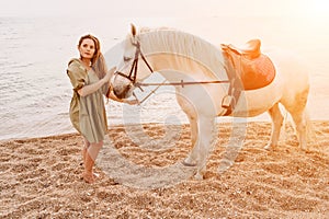 A woman in a dress stands next to a white horse on a beach, with the blue sky and sea in the background.