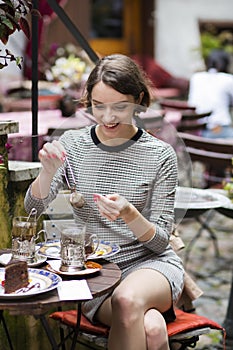 Woman at dress at street cafe brews tea