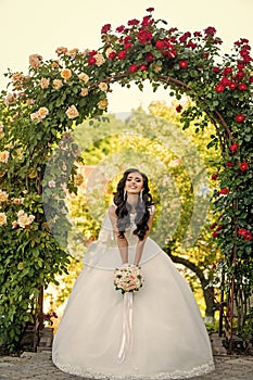 Woman with dress and veil at rose bouquet.