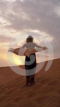 Woman in dress with view of desert sand in sunset light. Landscape