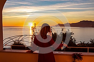 Woman in dress with view from a luxury apartment on the Mediterranean Sea in Praiano, Amalfi Coast, Campania, Italy, Europe.