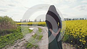 A woman in a dress is walking along a rural road.