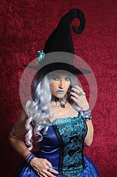 Woman Dressed as Blue Witch on Red Background