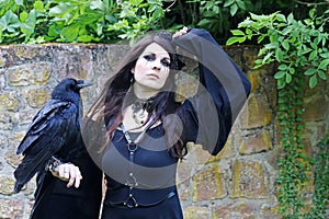 A woman dressed as a witch with a large raven on her hand