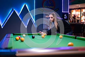 woman dressed in black crouching playing billiards with an uncertain face after the play.