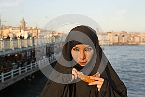 Woman dressed black headscarf, chador eating simit, istanbul, turkey