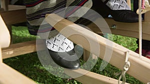 Woman Dressed in a Folk Dress Presses the Wooden Pedals of a Loom with Her Feet.