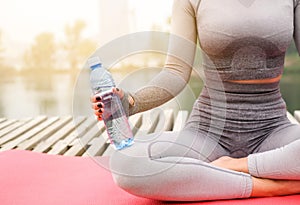 Woman dressed leggings and top with pink mat doing yoga on summer park.Healthy sport lifestyle concept