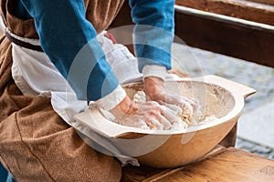 A woman dressed medieval costume sitting and kneading the fresh wheat dought. Healthy food and nutrition concept image