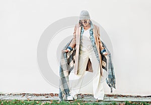 Woman dressed in multilayered autumn outfit: camel coat, denim j
