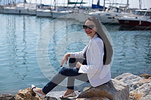 Woman dressed in nautical style sitting by seaside in yacht mari