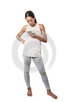 Woman dressed in sportswear looking at her smart phone on a white background