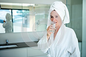 woman in a dressing gown drinking a glass of water