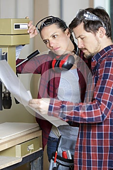 Woman drilling wood with help colleague